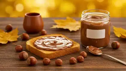 Pâte à tartiner chocolat noisette maison dans un pot en verre, servie sur une tartine dorée avec des noisettes entières autour.