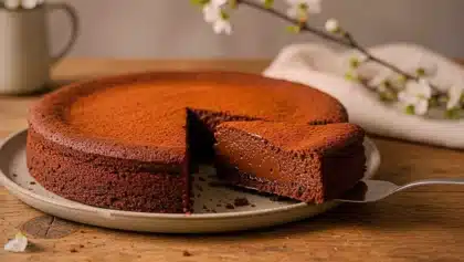Fondant au chocolat sans beurre, saupoudré de cacao, présenté sur une assiette avec une part découpée révélant une texture moelleuse.