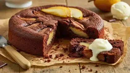 Gâteau au chocolat moelleux garni de poires fondantes, avec une part découpée montrant un cœur coulant et nappée de crème.
